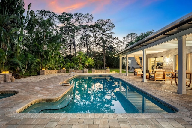 pool at dusk with a patio area and an outdoor hangout area