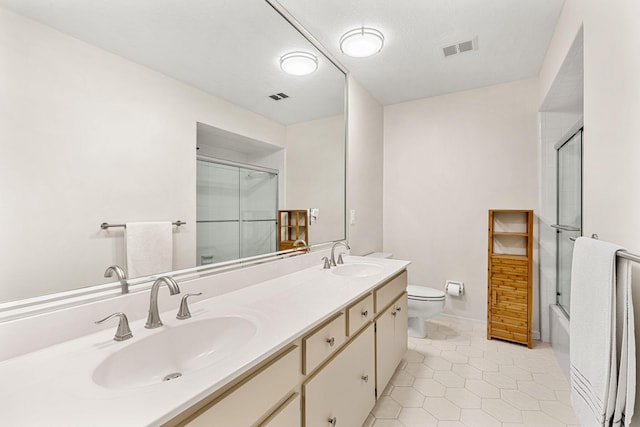 full bathroom with vanity with extensive cabinet space, toilet, shower / bath combination with glass door, tile floors, and dual sinks