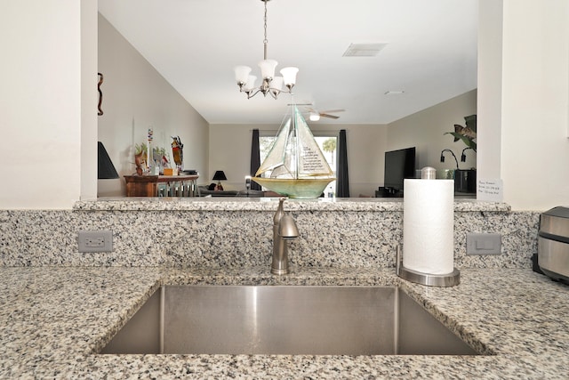 details featuring decorative light fixtures, light stone counters, sink, and ceiling fan with notable chandelier