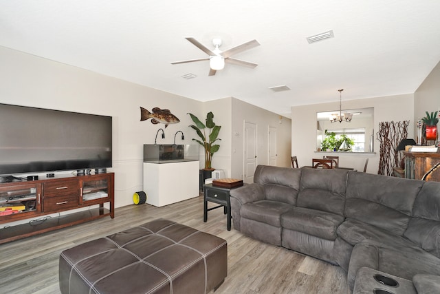 living room with hardwood / wood-style flooring and ceiling fan with notable chandelier