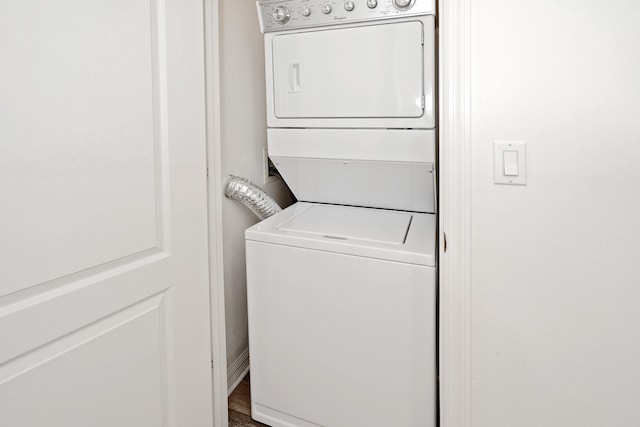 washroom with stacked washing maching and dryer and wood-type flooring