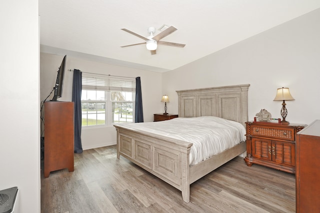 bedroom with ceiling fan, vaulted ceiling, and light hardwood / wood-style flooring