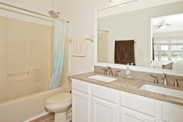 full bathroom with double sink vanity, shower / bath combo with shower curtain, hardwood / wood-style floors, ceiling fan, and toilet