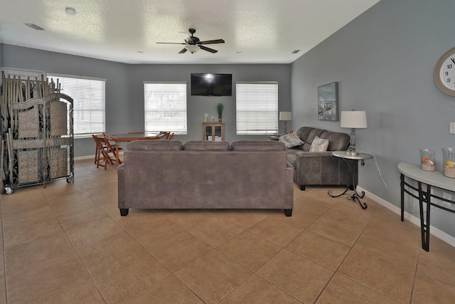 living room with light tile patterned flooring, ceiling fan, and a textured ceiling