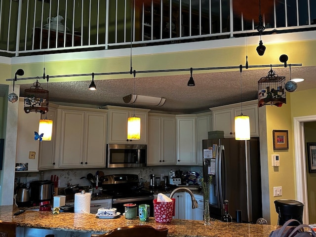 kitchen with backsplash, appliances with stainless steel finishes, a textured ceiling, and pendant lighting