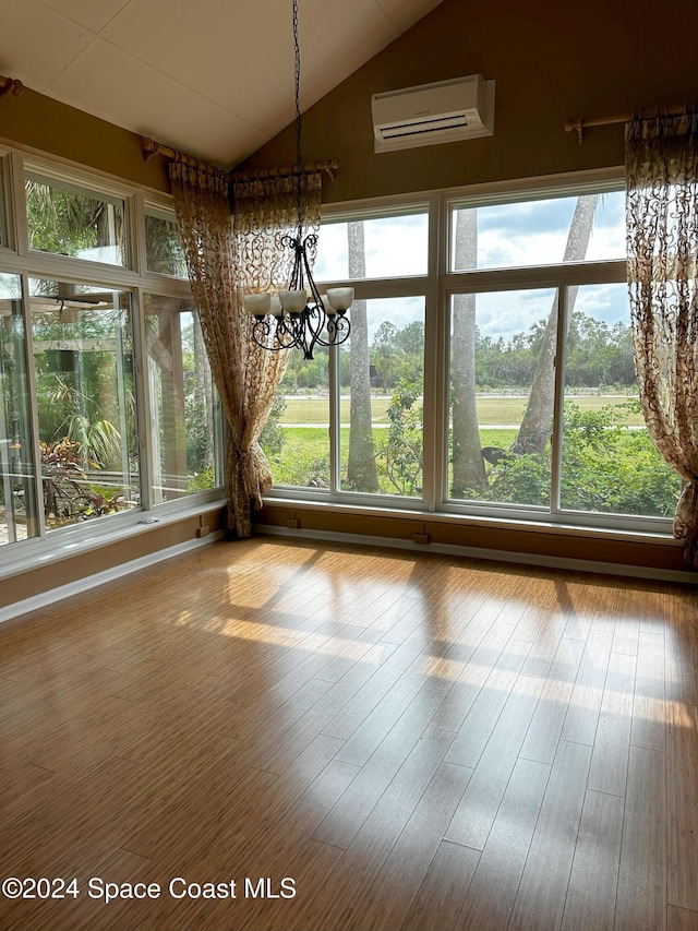 unfurnished dining area with a wall unit AC, a notable chandelier, wood-type flooring, and lofted ceiling