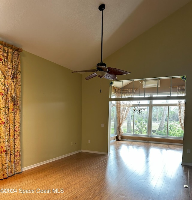 empty room featuring lofted ceiling, a textured ceiling, wood-type flooring, and ceiling fan