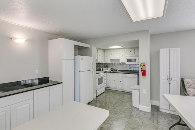 kitchen featuring light tile flooring, tasteful backsplash, white appliances, white cabinets, and sink