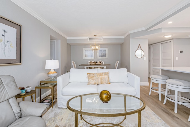 living room featuring an inviting chandelier, light hardwood / wood-style floors, and ornamental molding