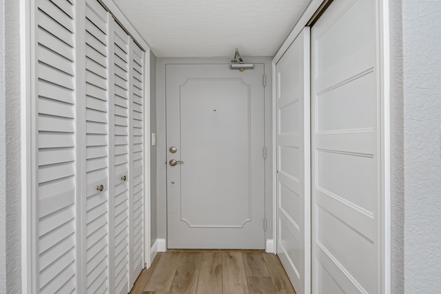 doorway featuring a textured ceiling and light hardwood / wood-style floors