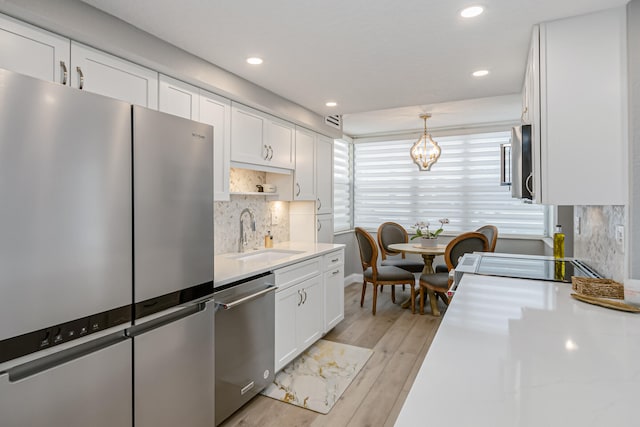 kitchen featuring light hardwood / wood-style floors, stainless steel appliances, a notable chandelier, tasteful backsplash, and sink