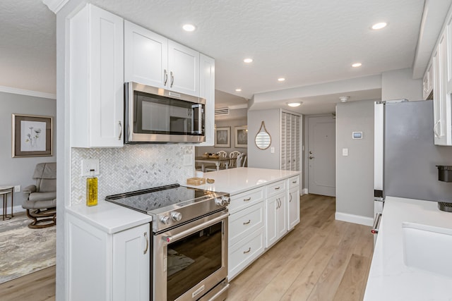 kitchen with a textured ceiling, light hardwood / wood-style flooring, appliances with stainless steel finishes, white cabinetry, and backsplash