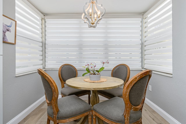 dining space with light hardwood / wood-style flooring and an inviting chandelier