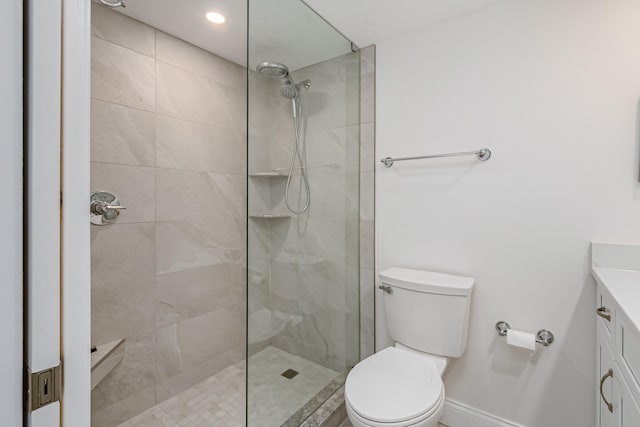 bathroom with toilet, a tile shower, and vanity