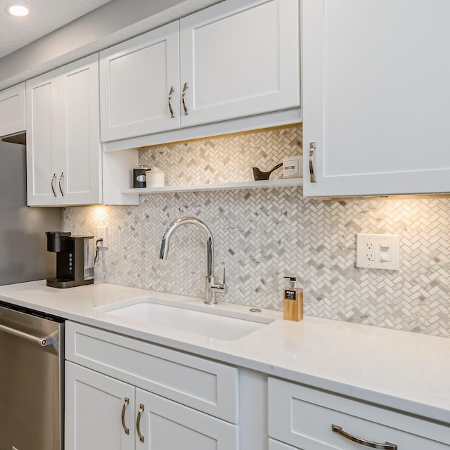 kitchen with white cabinets, stainless steel dishwasher, and tasteful backsplash