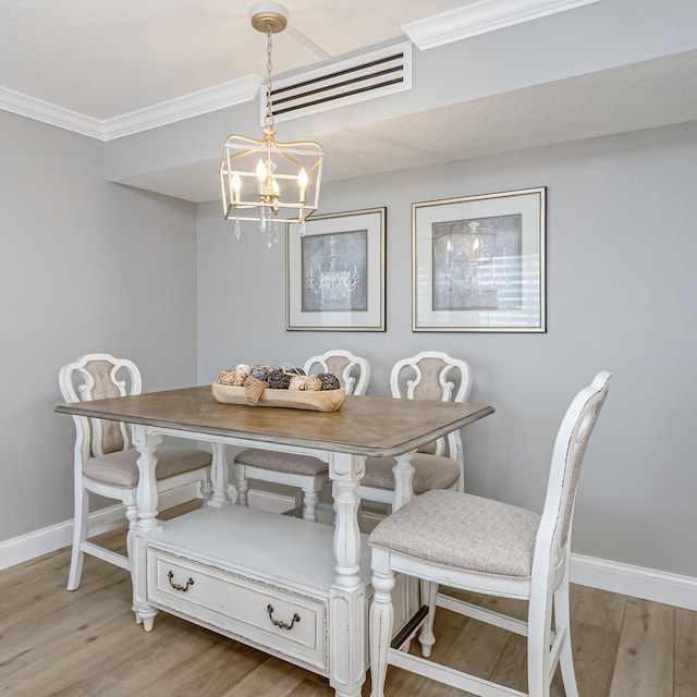 dining area featuring a chandelier, light hardwood / wood-style floors, and crown molding