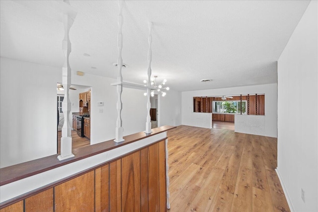 interior space with light hardwood / wood-style floors, a textured ceiling, and ceiling fan with notable chandelier