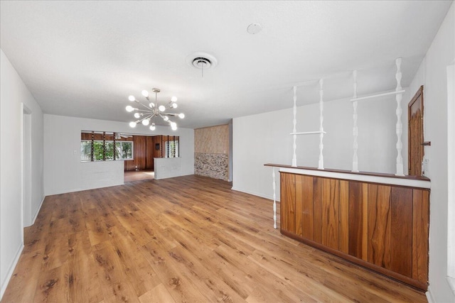 empty room with a notable chandelier and light hardwood / wood-style flooring