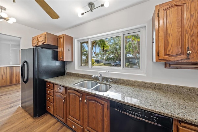 kitchen with light stone countertops, ceiling fan, black appliances, light hardwood / wood-style floors, and sink