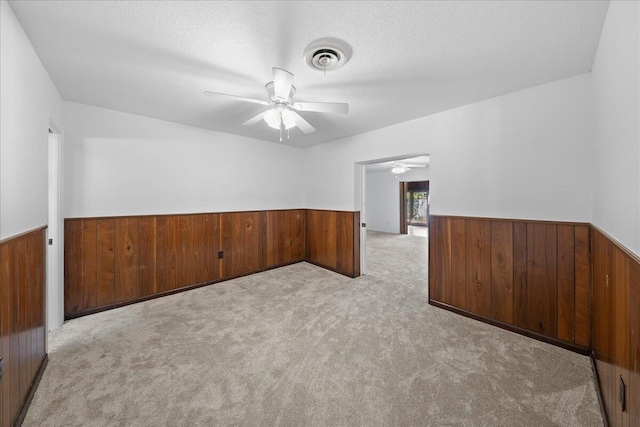 unfurnished room with a textured ceiling, light colored carpet, and ceiling fan