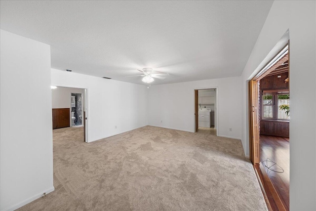 carpeted spare room with washer / clothes dryer and ceiling fan