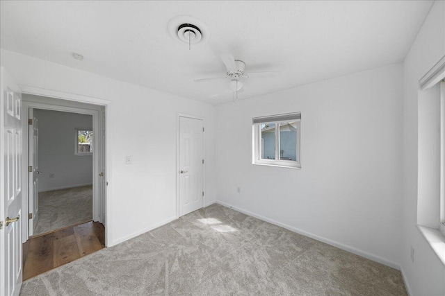 unfurnished bedroom with a closet, ceiling fan, hardwood / wood-style floors, and multiple windows