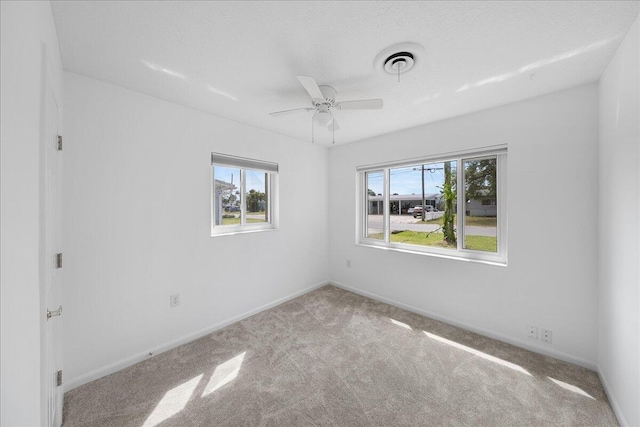 carpeted spare room with ceiling fan and a wealth of natural light