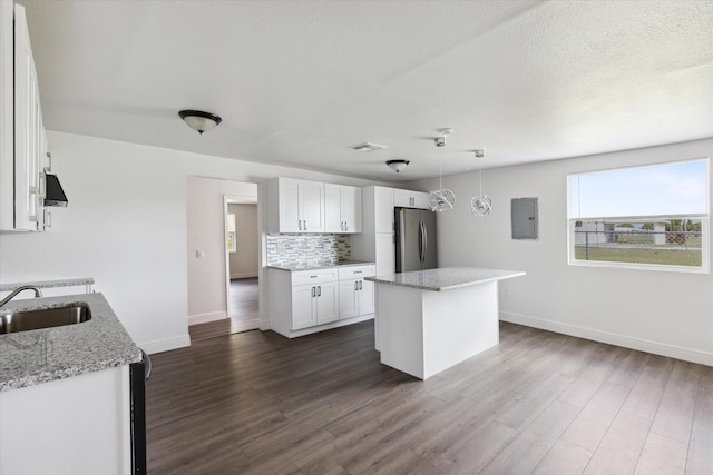 kitchen featuring light stone countertops, dark hardwood / wood-style floors, sink, white cabinets, and stainless steel refrigerator