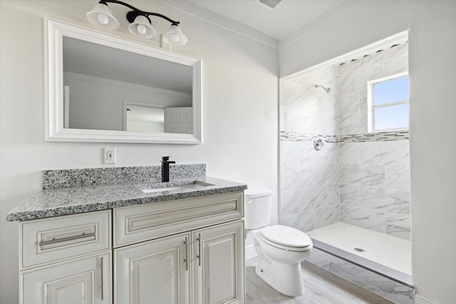 bathroom with vanity, a tile shower, wood-type flooring, and toilet