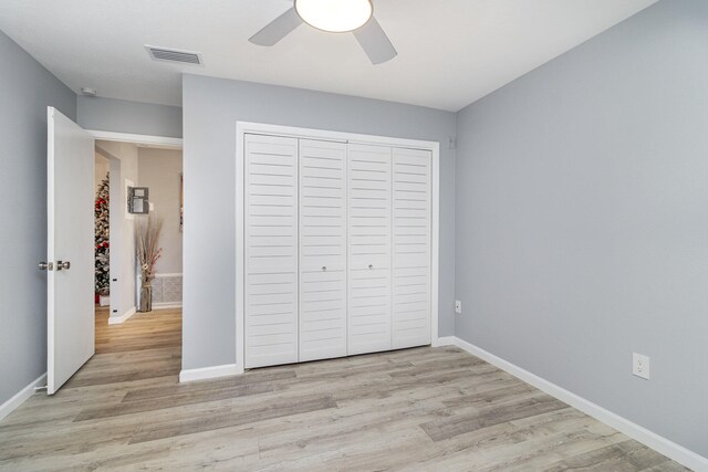 unfurnished bedroom with ceiling fan, a closet, and light wood-type flooring