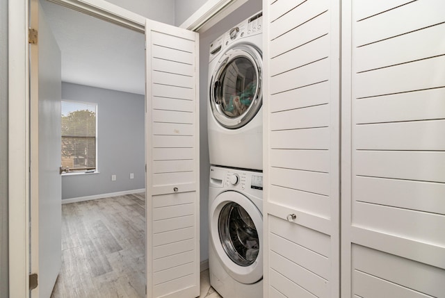 laundry area with stacked washer / dryer and light wood-type flooring