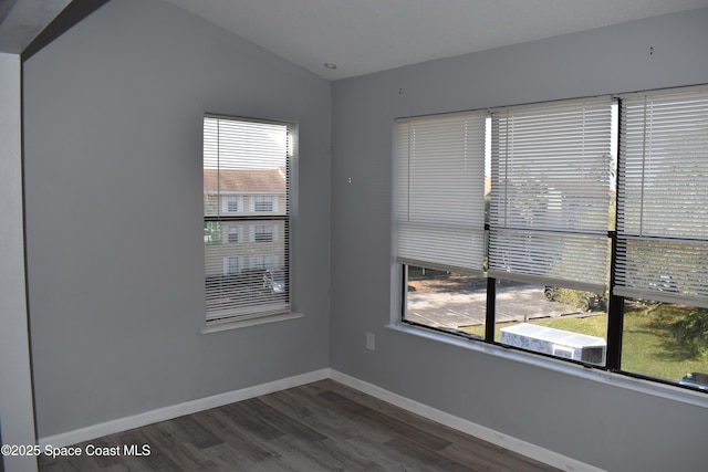 spare room featuring dark hardwood / wood-style floors and vaulted ceiling