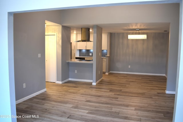 kitchen with tasteful backsplash, wood-type flooring, white cabinets, island exhaust hood, and decorative light fixtures