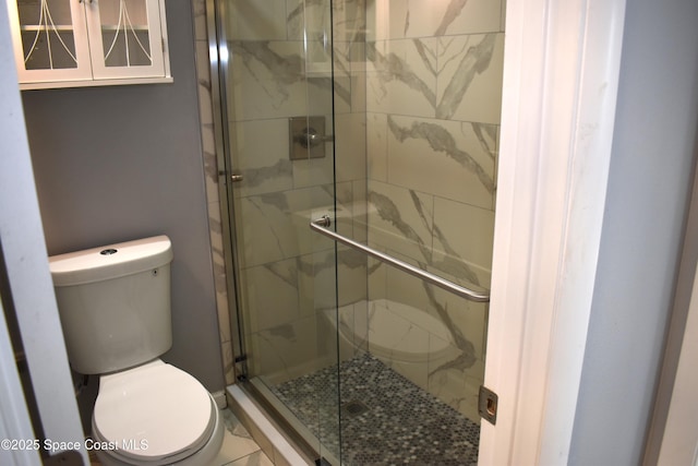 bathroom featuring a shower with shower door and toilet