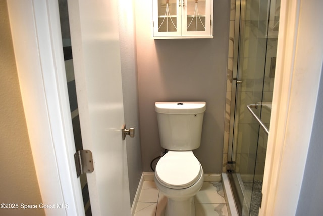 bathroom with toilet, tile patterned flooring, and a shower with door