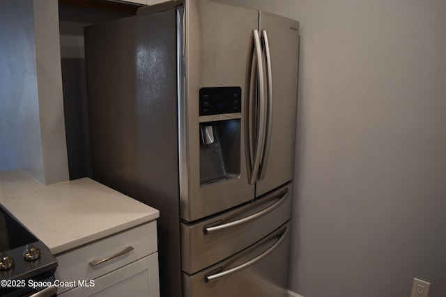 kitchen with stainless steel refrigerator with ice dispenser and white cabinetry