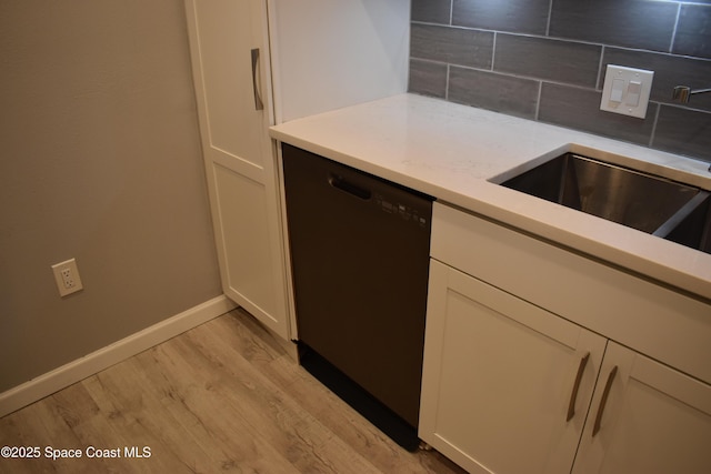 kitchen with sink, tasteful backsplash, white cabinetry, light wood-type flooring, and dishwasher