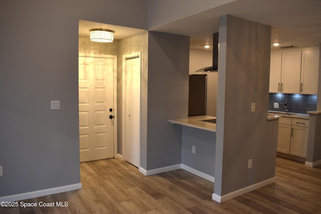 kitchen featuring white cabinetry, stainless steel fridge, light hardwood / wood-style flooring, and backsplash