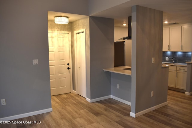 kitchen with light hardwood / wood-style flooring, stainless steel fridge, white cabinetry, tasteful backsplash, and extractor fan