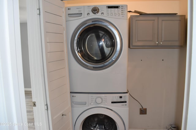 laundry room with cabinets and stacked washing maching and dryer