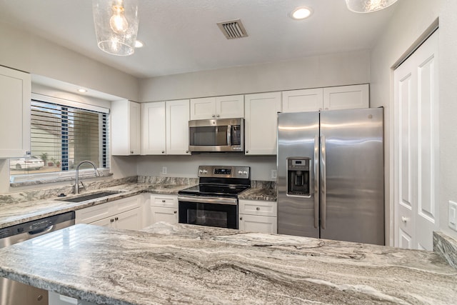 kitchen featuring white cabinets, appliances with stainless steel finishes, hanging light fixtures, and sink