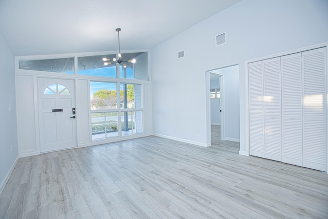 entryway featuring high vaulted ceiling, light wood-type flooring, and an inviting chandelier