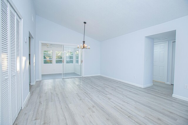 empty room with light hardwood / wood-style floors, high vaulted ceiling, and a chandelier