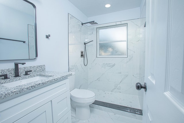 bathroom featuring toilet, a tile shower, and vanity