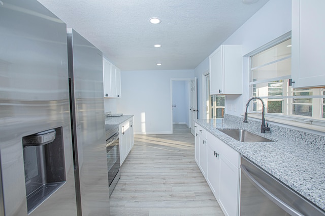 kitchen with sink, white cabinets, stainless steel appliances, and light wood-type flooring