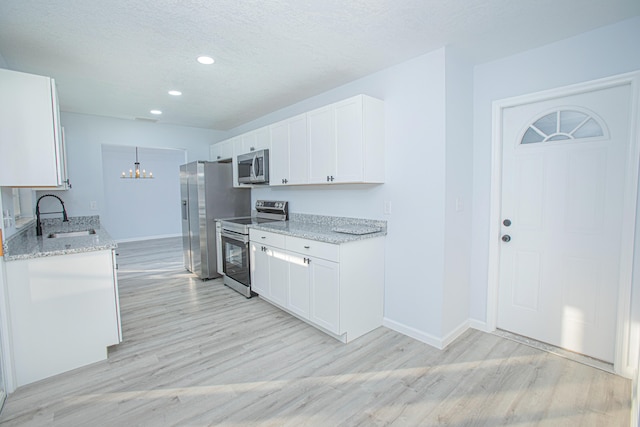 kitchen with white cabinetry, sink, appliances with stainless steel finishes, and light hardwood / wood-style flooring