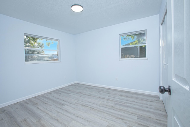 spare room with plenty of natural light, light hardwood / wood-style floors, and a textured ceiling