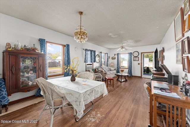 dining room with plenty of natural light, wood-type flooring, and ceiling fan with notable chandelier