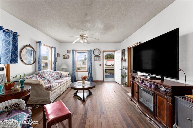 living room with dark hardwood / wood-style flooring, a textured ceiling, and ceiling fan