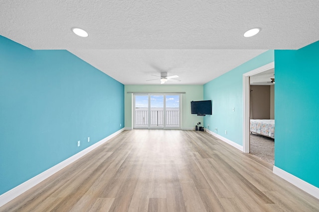 unfurnished living room with ceiling fan, light hardwood / wood-style floors, and a textured ceiling